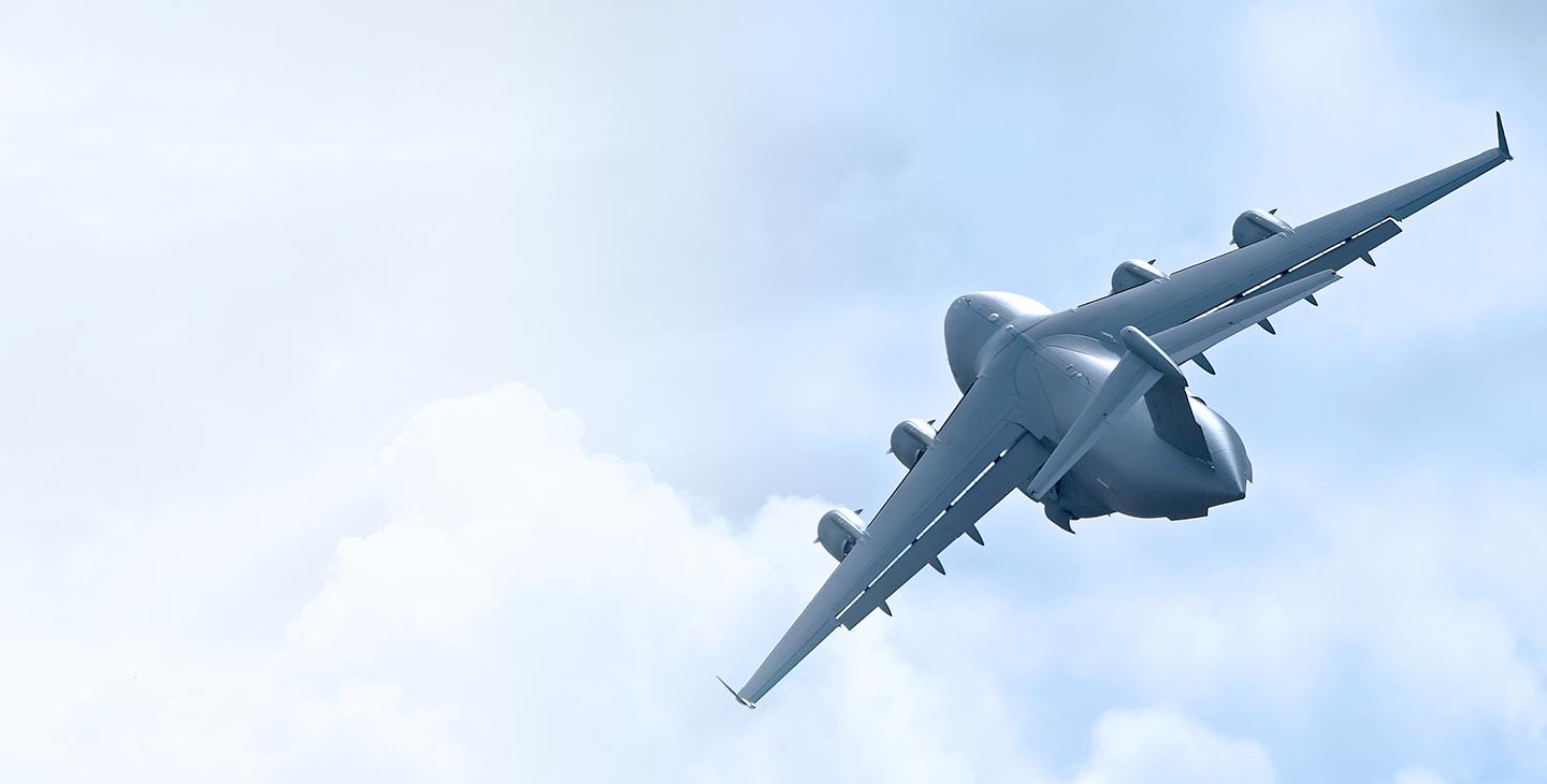 A C-17 aircraft taking off into the clouds