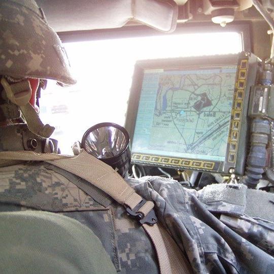 Soldier in a vehicle monitoring data from Blue Force Tracking program on a monitor