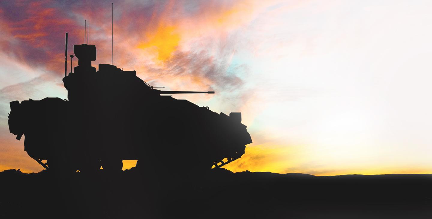 Silhouette of a military tank driving against the sunset