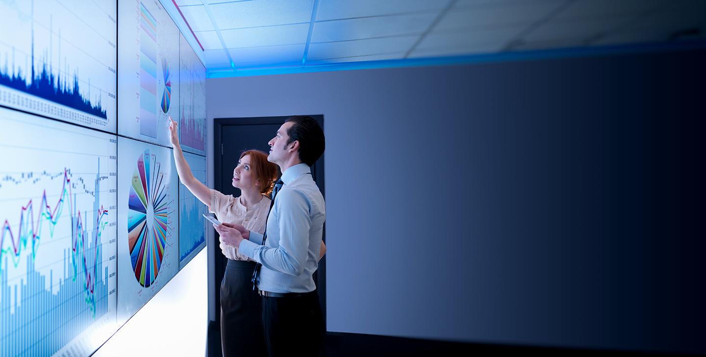 Man and woman discussing managed security data projected on the wall
